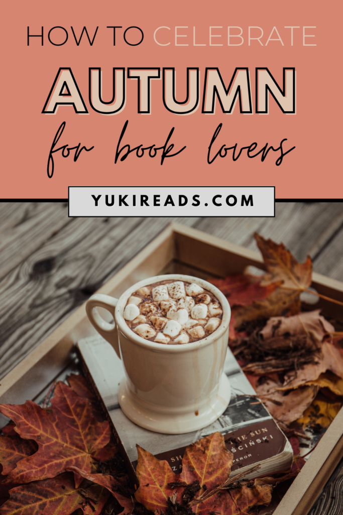 How to celebrate autumn for book lovers with a great book and a pumpkin spice latte with marshmallows surrounded by fall leaves.