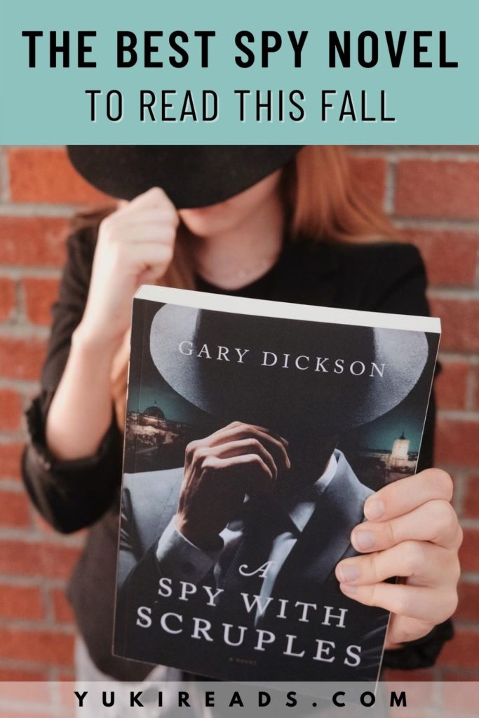 Bookstagrammer with a black fedora and a black blazer holding the historical fiction novel A Spy With Scruples by Gary Dickson in Palo Alto, California.