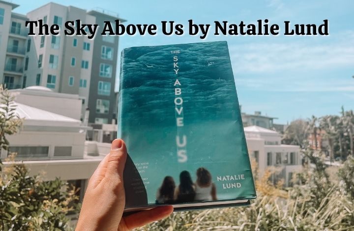 A book blogger holds the young adult novel The Sky Above Us by Natalie Lund.